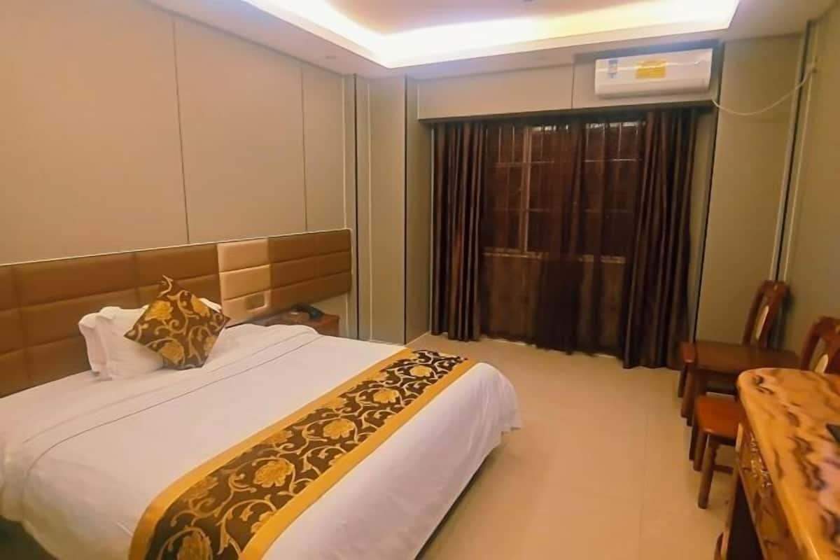 Una habitación de hotel con una cama, un comedor de madera y un ventanal con cortinas.