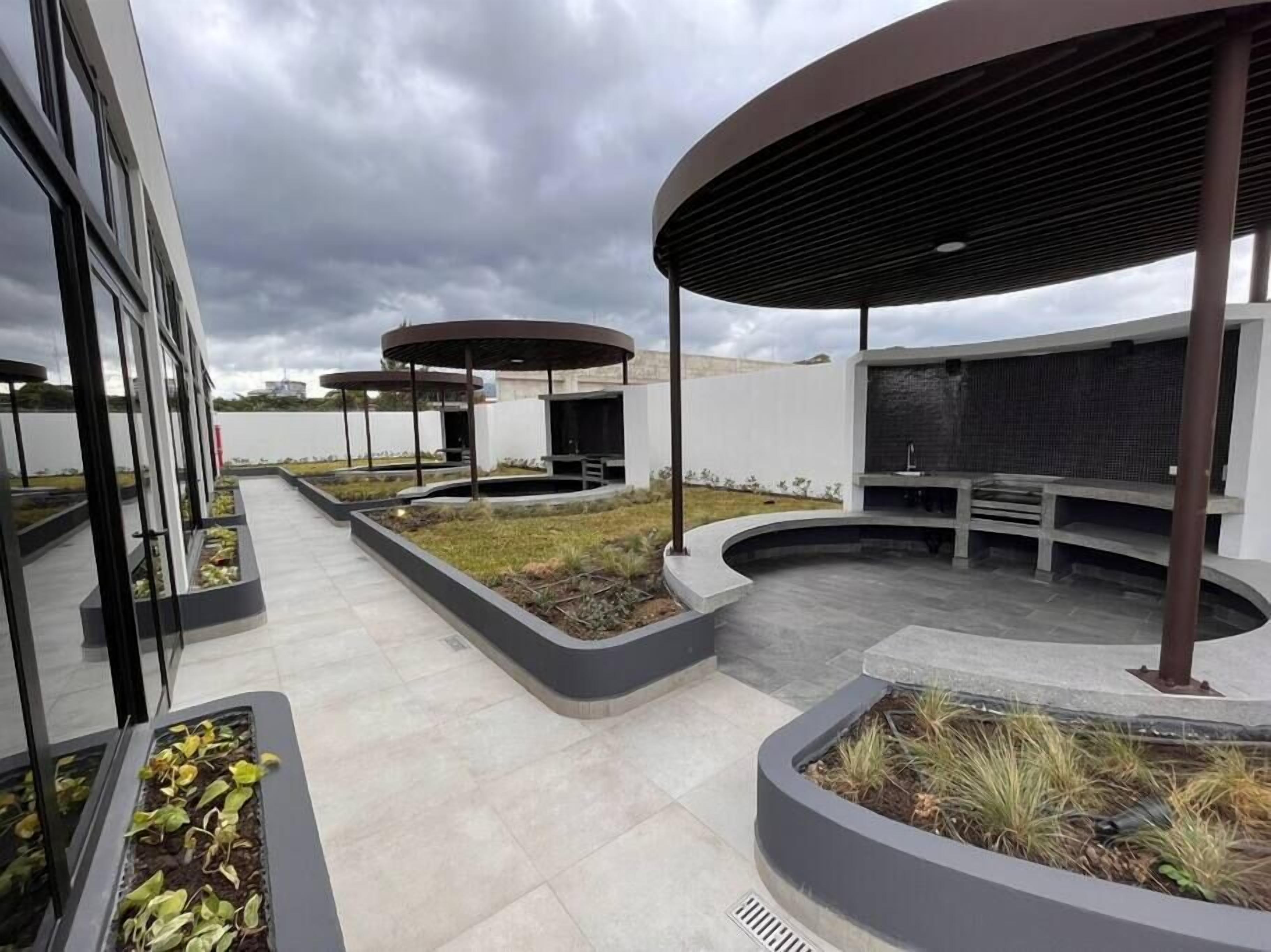 Une terrasse sur le toit, dotée d’un mobilier d’extérieur moderne, de jardinières verdoyantes et offrant une vue sur les bâtiments environnants.