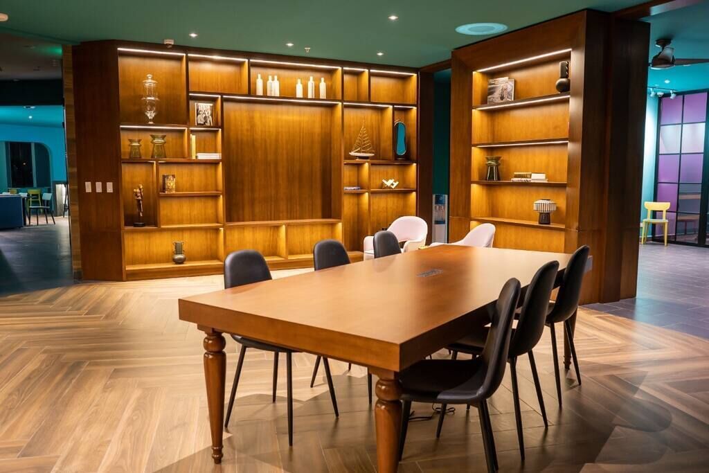 Ein Konferenzraum mit Holztisch und -stühlen, umgeben von Holzregalen mit verschiedenen Gegenständen.