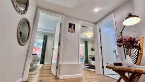 A hallway with wooden flooring, white walls, and a dining area with a table and chairs. - Garden Retreat | Firepit | 911Mbps | W/D| Smart TV (San Francisco)