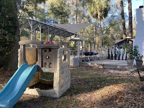 A playground with a slide, a picnic area, and barbecue grills.