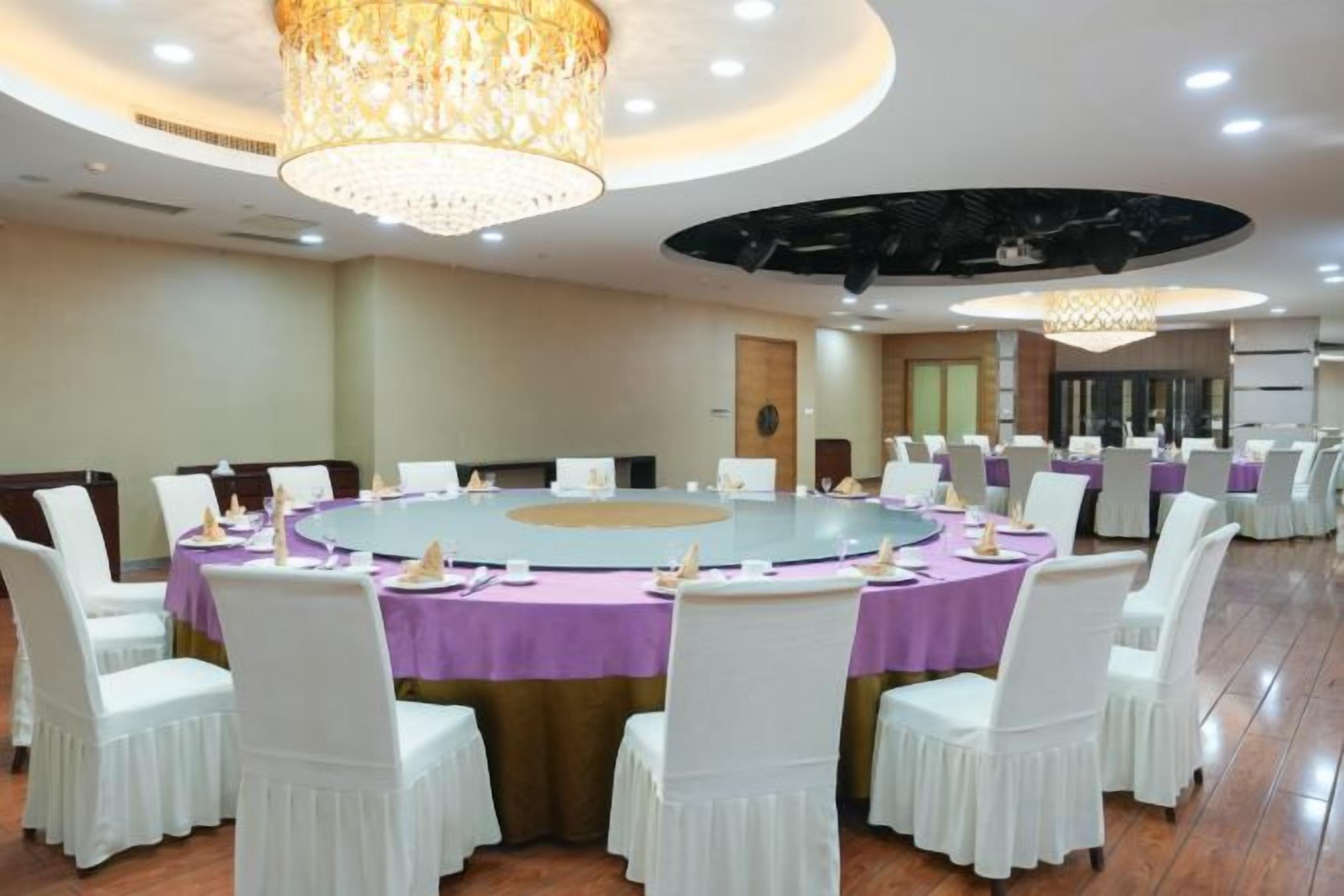 A conference room with a large oval table, white chairs, and a chandelier.