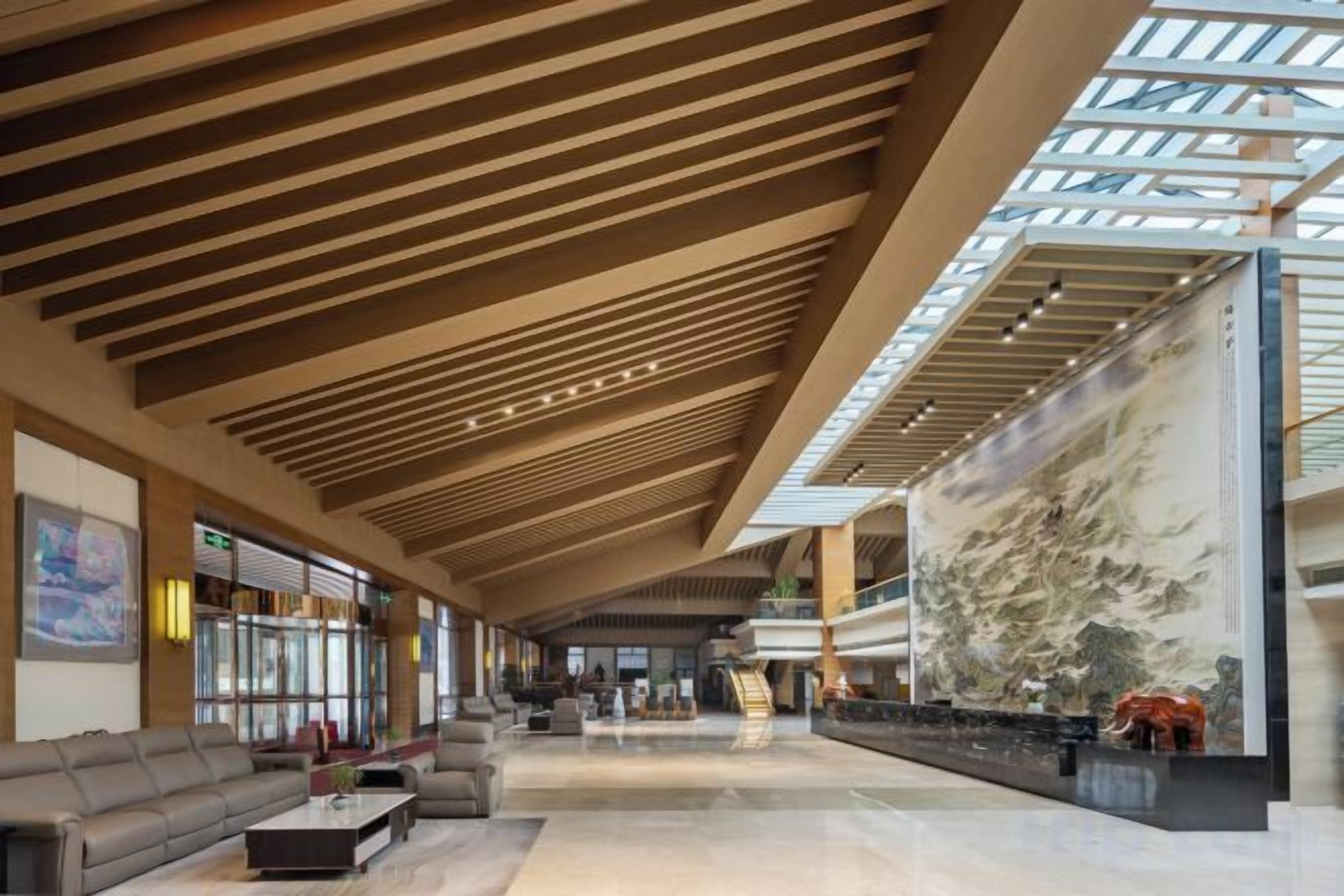 Un'ampia hall con soffitto alto, un grande murale e un'area relax.