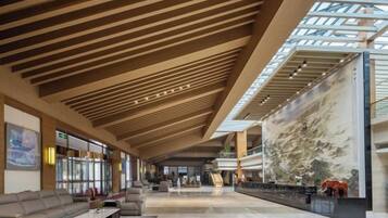 Un'ampia hall con soffitto alto, un grande murale e un'area relax.