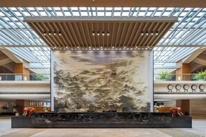 A spacious lobby with a large mural, a reception desk, and a modern ceiling design. - Fushan Hotel Yantai (Yantai)
