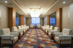 A hotel conference room with rows of chairs, a patterned carpet, and a chandelier. - Fushan Hotel Yantai (Yantai)