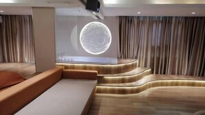 A modern hotel room with a curved sofa, a large wall mural, and a wooden floor. - Fan She Fashion Hotel (Heyuan)
