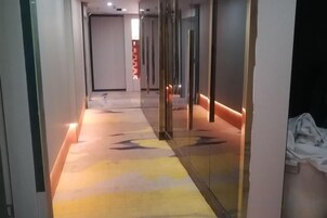 A hallway with a patterned carpet, glass doors, and a red accent wall.