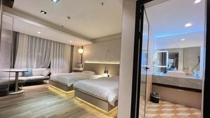 A modern hotel room with two beds, a sofa, a small table, and a bathroom with a mirror. - Fan She Fashion Hotel (Heyuan)