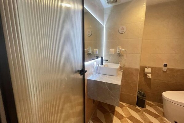 A modern bathroom with a marble countertop, a toilet, and a trash bin. - Fan She Fashion Hotel (Heyuan)