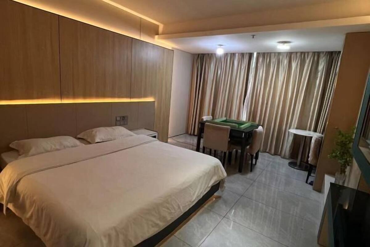 A hotel room with a large bed, a desk with a chair, a small table, and a green pool table.