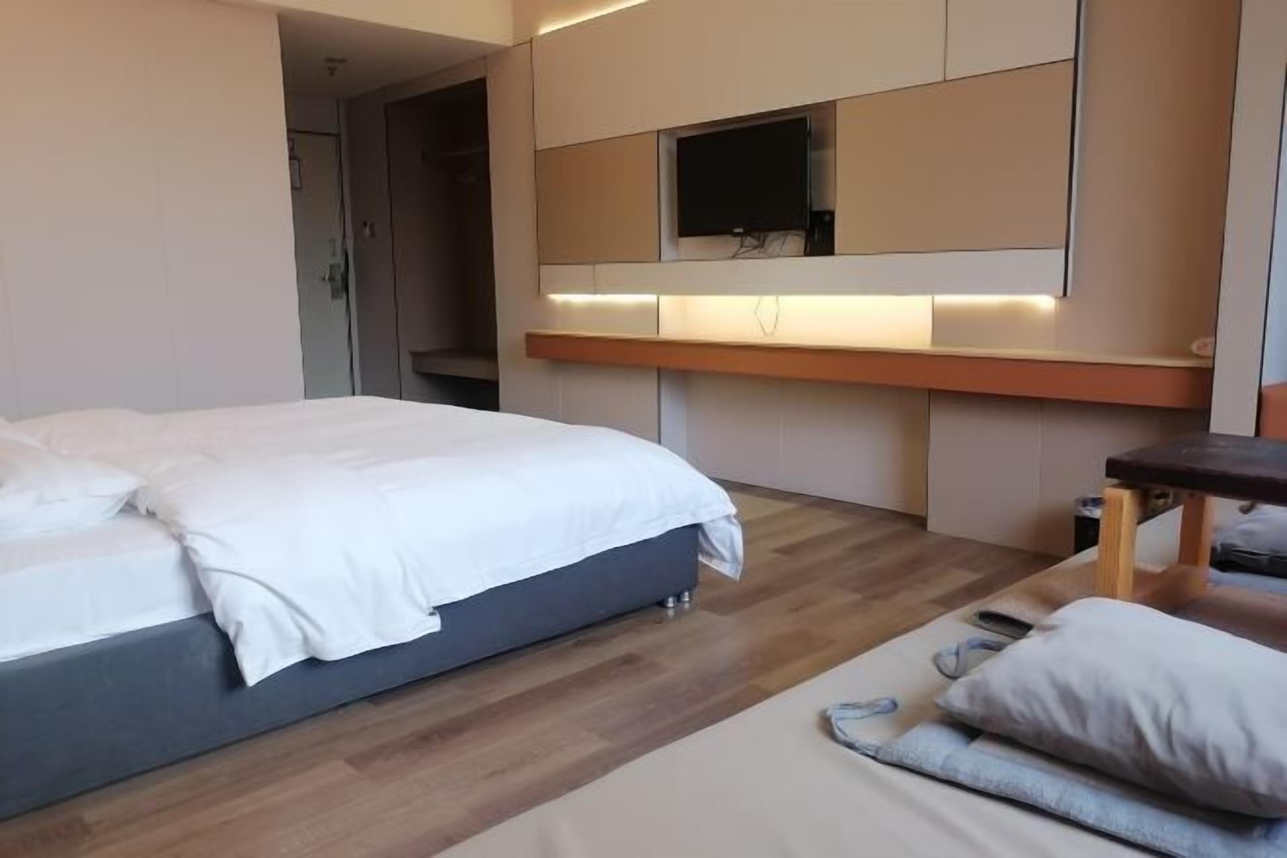 Habitación de hotel moderna con una cama grande, un escritorio y un televisor montado en la pared.