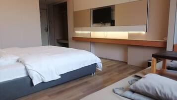 Habitación de hotel moderna con una cama grande, un escritorio y un televisor montado en la pared.