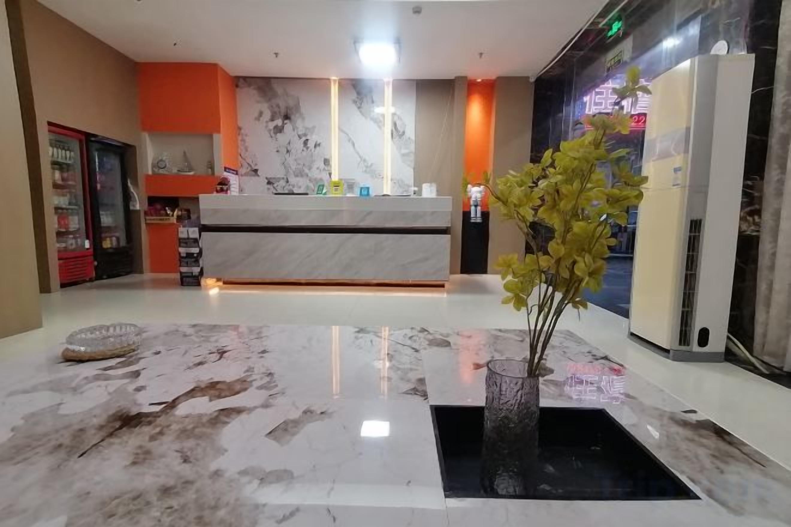 Ein Hotel-Empfangsbereich mit Marmorzauber, einer Rezeption, einer Pflanze und einem Automaten.