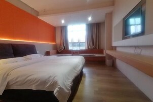 Una habitación de hotel moderna con una cama grande, una zona de estar y vistas al exterior.