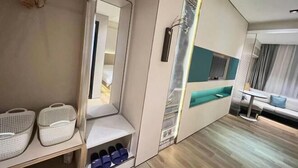 A modern hotel room with a built-in wardrobe, a seating area with a table, and a large mirror. - Fan She Fashion Hotel (Heyuan)
