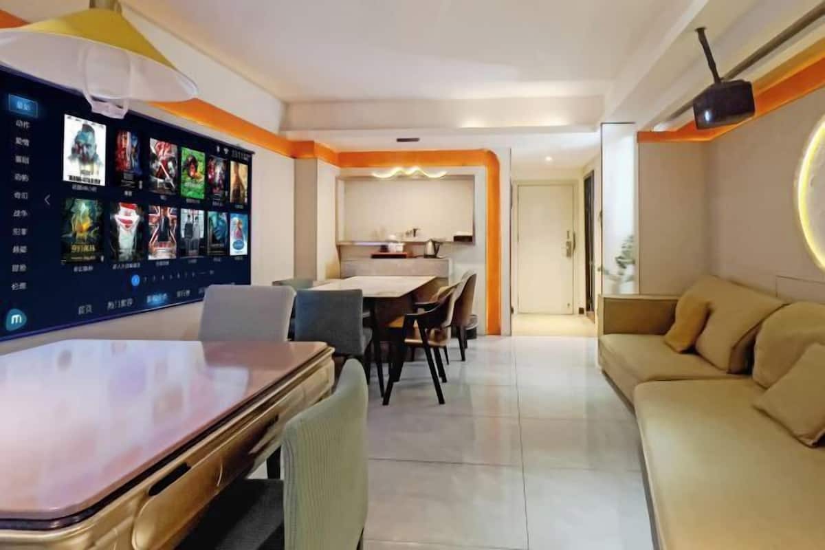 A modern living room with a flat-screen TV, a dining area, and a sofa.