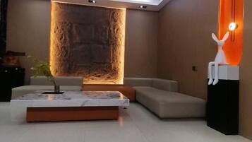A modern living room with a sectional sofa, a coffee table, and a decorative wall feature.