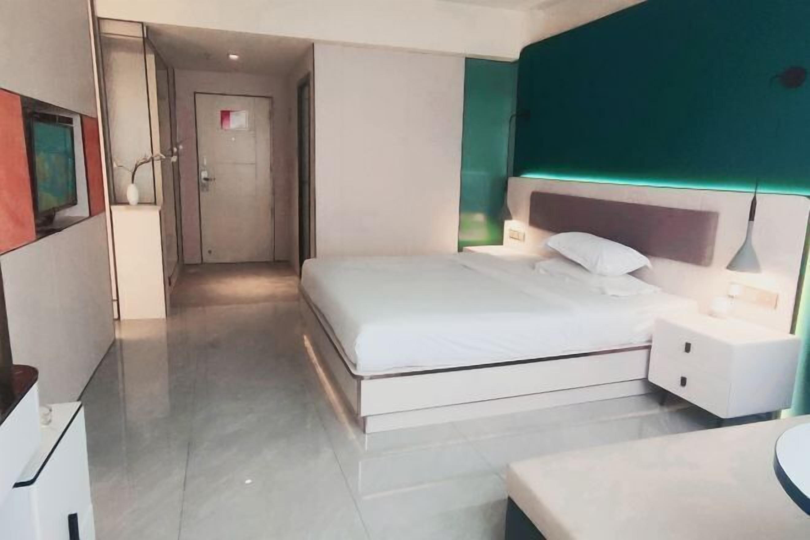 A modern hotel room with a large bed, bedside tables, and a bathroom with a mirror.