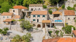 Un village construit en pierre, avec des toits en tuiles de terre cuite, des rues étroites et une place centrale agrémentée d’une piscine.