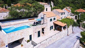 A stone building with a swimming pool, outdoor seating, and a view of the surrounding area.