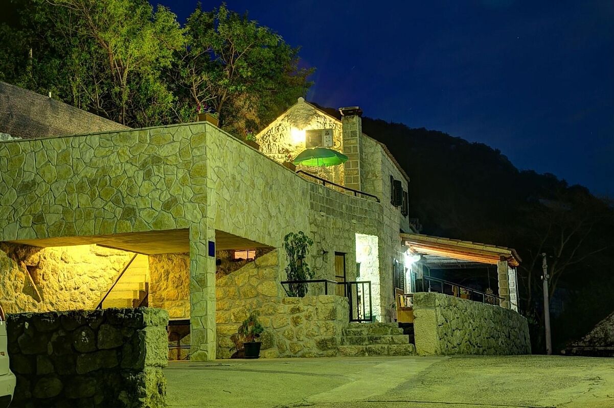 Un edificio de piedra con un balcón, una escalera y un paraguas verde.