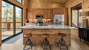 A kitchen with wooden cabinets, a marble countertop, and a large island with stools. - "This cabin is absolutely beautiful and in a gorgeous and quiet area!" (Sevierville)