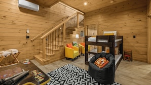 A wooden interior with a bunk bed, a sofa, a desk with a computer, and a staircase. - "This cabin is absolutely beautiful and in a gorgeous and quiet area!" (Sevierville)