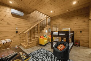 A wooden interior with a bunk bed, a sofa, a coffee table, and a staircase.