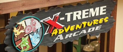 Une enseigne pour « X-TREME Adventures Arcade », avec un motif coloré en forme d’engrenage.