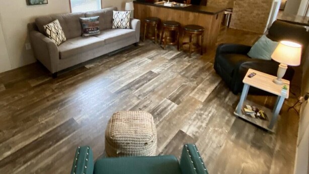 A compact living space with a sofa, a dining area with stools, a small table with a lamp, and a kitchenette. - Rainbow River Bungalow D (Dunnellon)