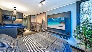 Une chambre moderne avec vue sur la ville, un grand lit et un téléviseur fixé au mur.