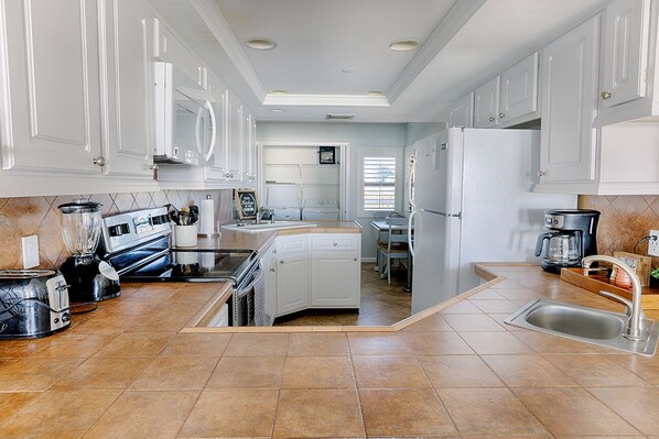A modern kitchen with white cabinets, a central island, and a built-in dishwasher. - Destin Beachfront Paradise! Amazing Views! (Destin)