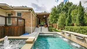 A swimming pool with a wooden deck and steps leading to a covered area. - East Dallas 3BR Home with Pool, Spa & Fireplace (Dallas)