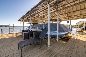 Eine überdachte Terrasse mit einem Boot, einer Sitzgelegenheit und Blick auf das Wasser.