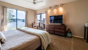 Une chambre d’hôtel équipée d’un lit, d’une télévision, d’un bureau et offrant une vue sur un plan d’eau.