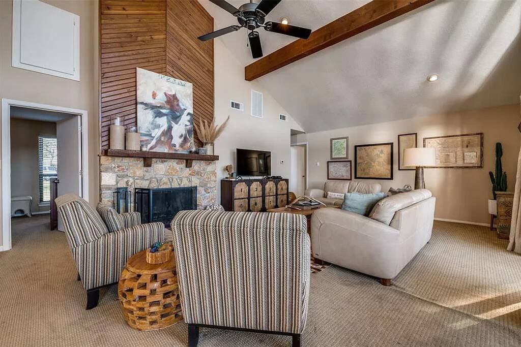 Un salon spacieux doté d’une cheminée, de fauteuils à rayures, d’un canapé et d’un ventilateur de plafond.