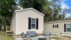 A mobile home with a deck, outdoor seating, and a sign indicating guest parking. - Rainbow River Bungalow F (Dunnellon)