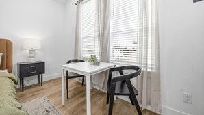 A bedroom with a bed, bedside table, lamp, and a window with curtains.