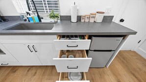 A kitchen with a grey countertop, white cabinets, and a built-in drawer unit.