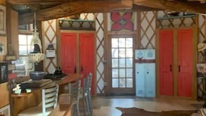 A rustic interior with a wooden bar, red doors, and a cowhide rug. - Three-story Blue Ridge Yurt getaway (Pilot)