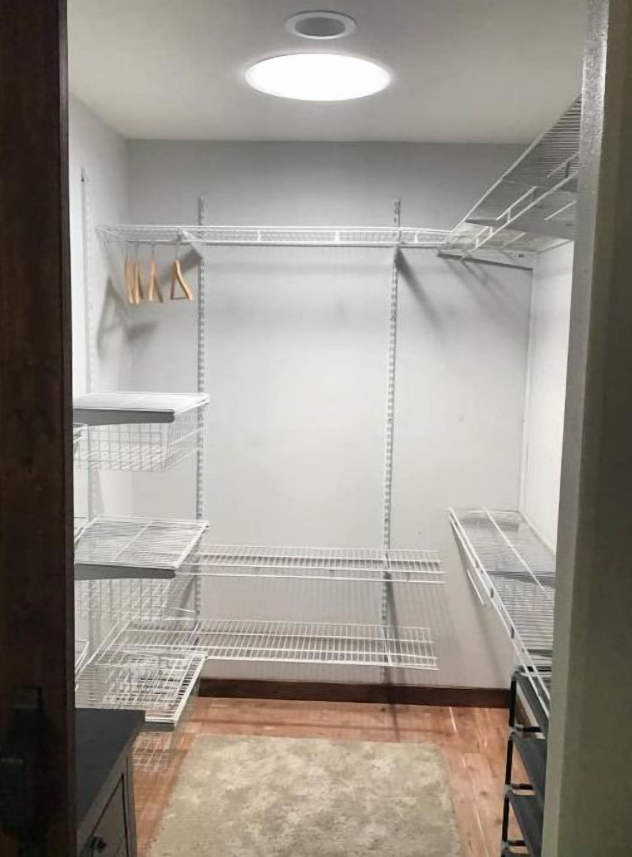 Un armario abierto con estanterías metálicas y suelo de madera.