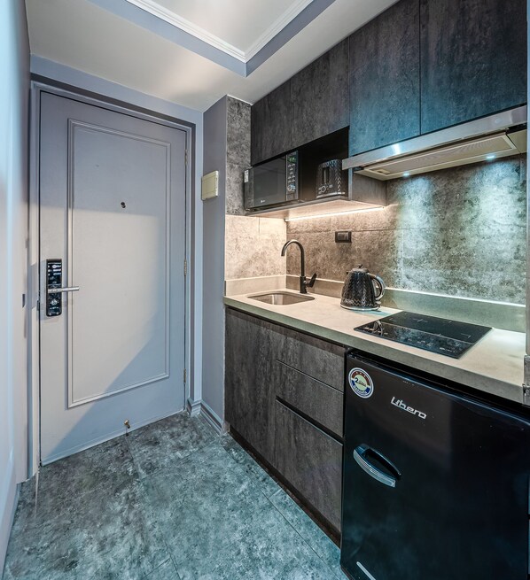 A modern kitchen with dark cabinetry, a built-in microwave, a sink, and a dishwasher.