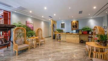 Un vestíbulo de hotel con mostrador de recepción, zona de estar y una escalera.
