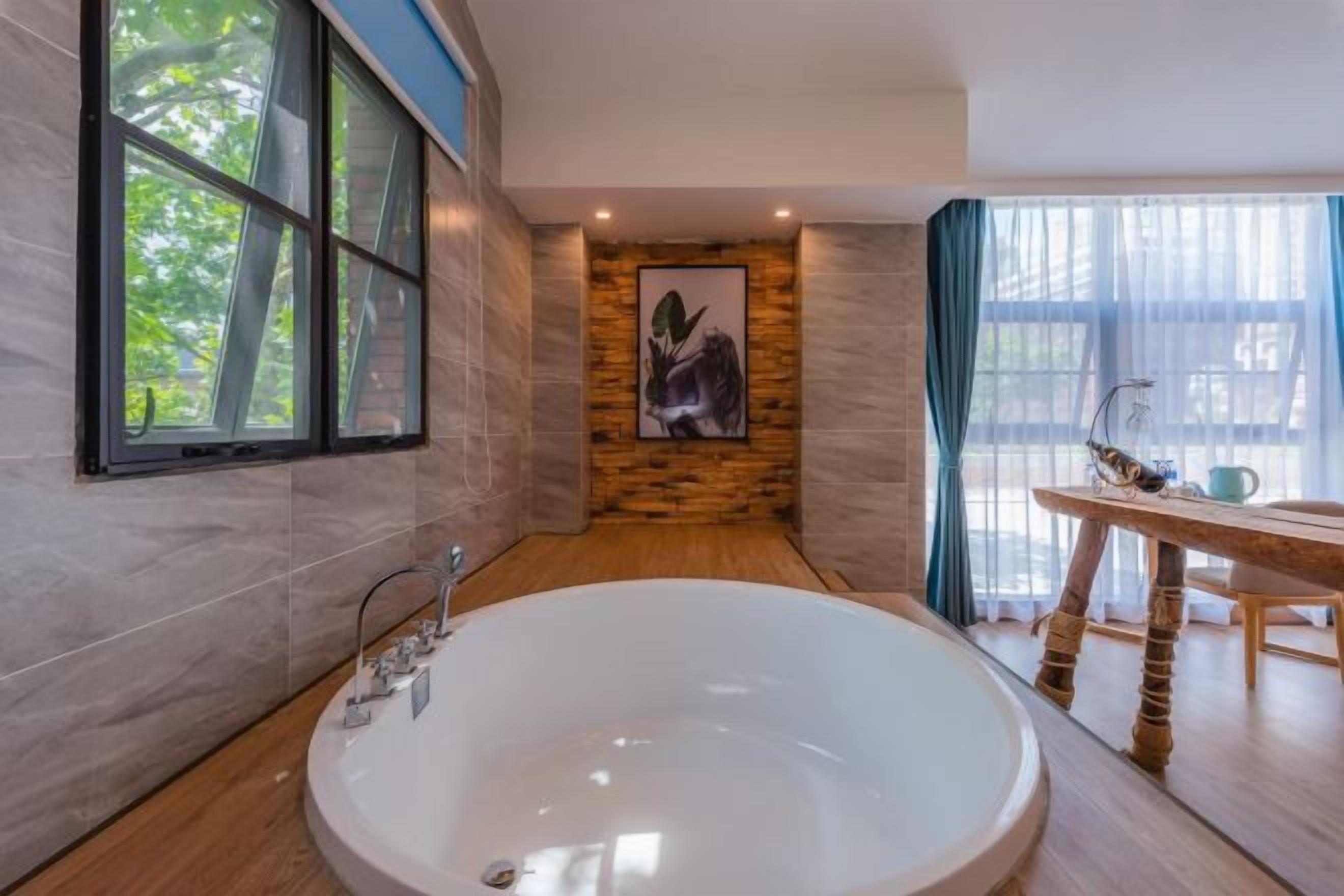 Un baño moderno con una bañera grande, un revestimiento de pared de madera, una obra de arte enmarcada y un área de comedor con mesa y sillas.
