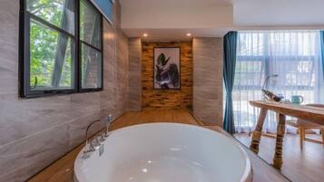 Un baño moderno con una bañera grande, un revestimiento de pared de madera, una obra de arte enmarcada y un área de comedor con mesa y sillas.