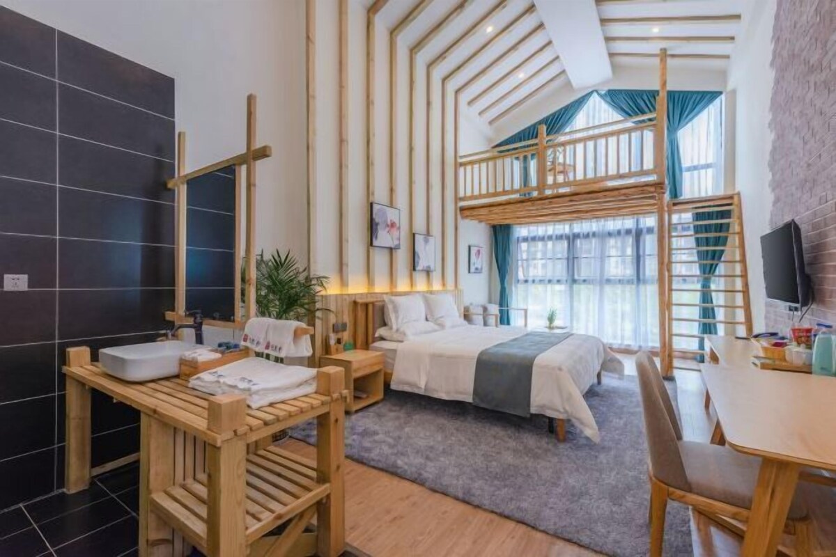 Quarto de hotel moderno com beliche, mesa de madeira com pia, janela ampla e parede de tijolos.