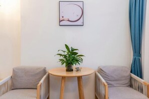 A room with two wooden chairs, a small round table with a plant, and a framed abstract artwork on the wall. - Duyun JuZhi · Memory Hotel (Qiannan Normal University) (Duyun)