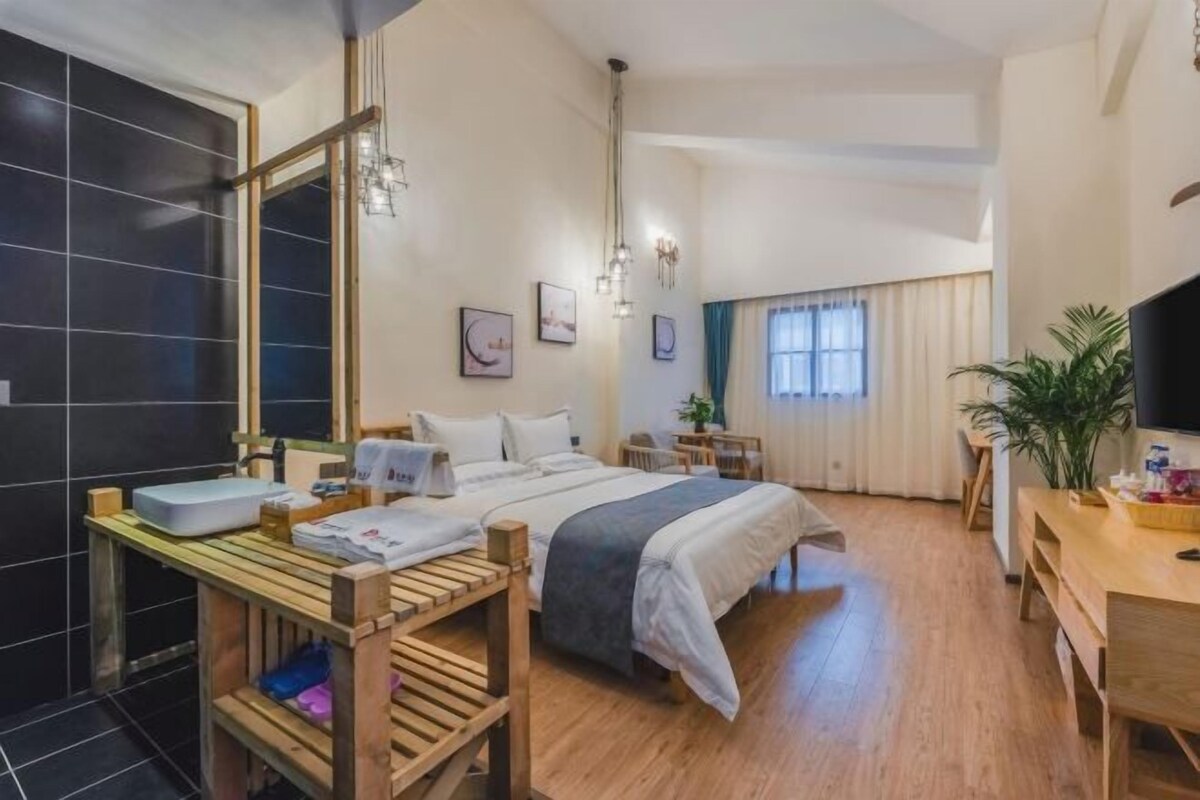 Quarto de hotel com cama, mesa de cabeceira, televisão e um espelho grande.
