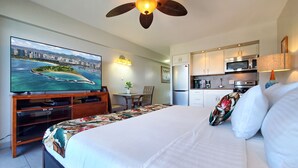 Una habitación de hotel con una cama, televisión, escritorio y kitchenette.